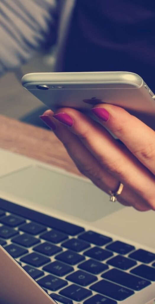 Woman with painted fingernails wearing a ring and holding an iPhone